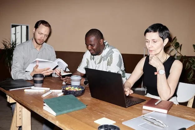 A diverse group of people sitting around a table, participating in a cybersecurity training session. Laptops and informational materials are on the table, and the atmosphere is engaging.