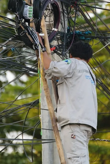 A close-up photo of fiber optic cables being installed in a rural area. Workers are seen carefully connecting the cables, highlighting the physical effort and technology involved in expanding broadband infrastructure.