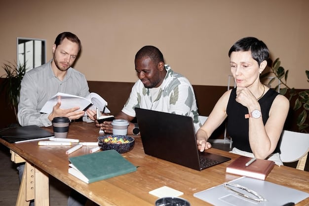A diverse group of people sitting around a table, participating in a cybersecurity training session. Laptops and informational materials are on the table, and the atmosphere is engaging.