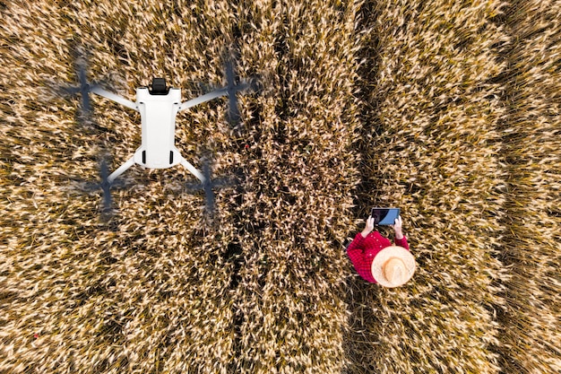A farmer examining a crop field with a drone flying overhead. The drone is equipped with sensors that collect data on crop health, pest infestations, and disease outbreaks. The image showcases the integration of drone technology in wireless precision agriculture.