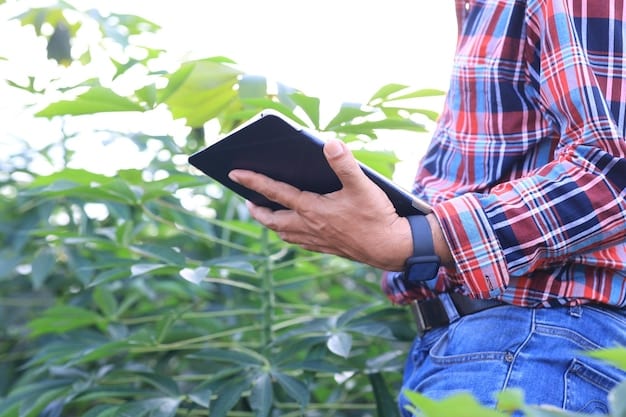 A farmer using a tablet to monitor and control an automated irrigation system in a field. The screen displays a real-time map of the field, showing soil moisture levels and areas under irrigation. The background features rows of healthy crops, highlighting the system's effectiveness in maintaining optimal growing conditions.